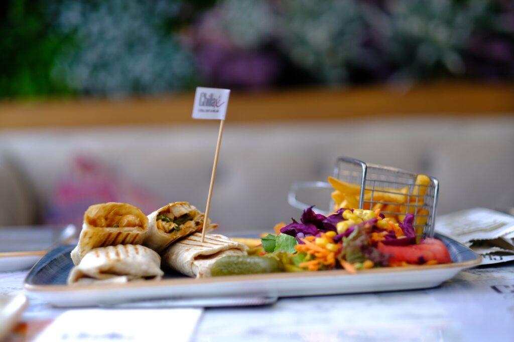 A mouthwatering assortment of wraps, salad, and fries served on a tray, perfect for food photography enthusiasts.