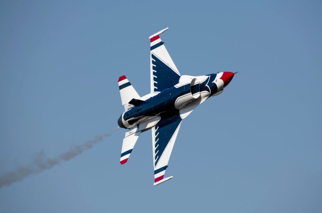High-speed military jet performing an aerobatic maneuver against a clear sky.
