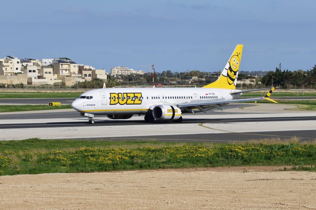 Buzz Airline aircraft on the runway at a sunny airport, ready for takeoff.