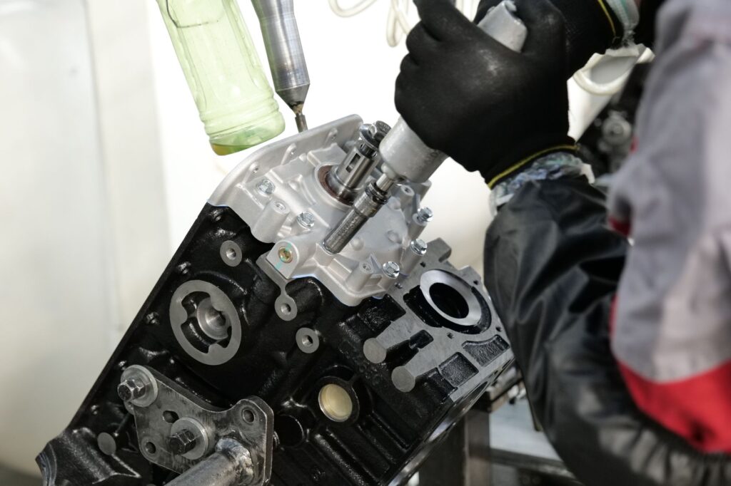 Skilled mechanic working on engine assembly with precision tools in factory setting.