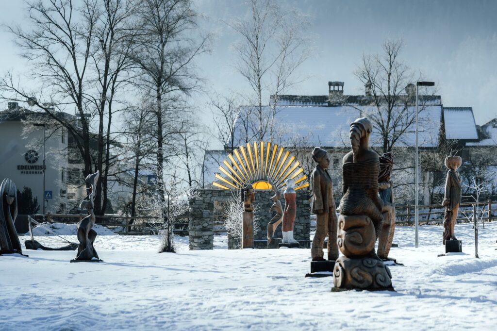 Outdoor sculptures in a snowy landscape with winter trees and buildings.