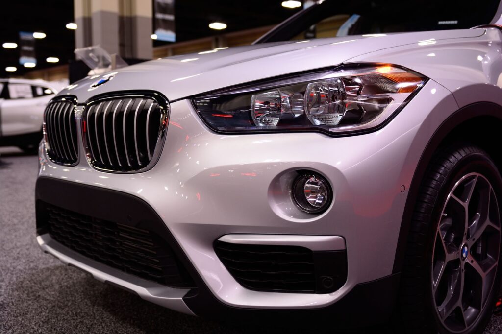 Close-up of a luxury car's front end showcasing its sleek design at an indoor auto show.