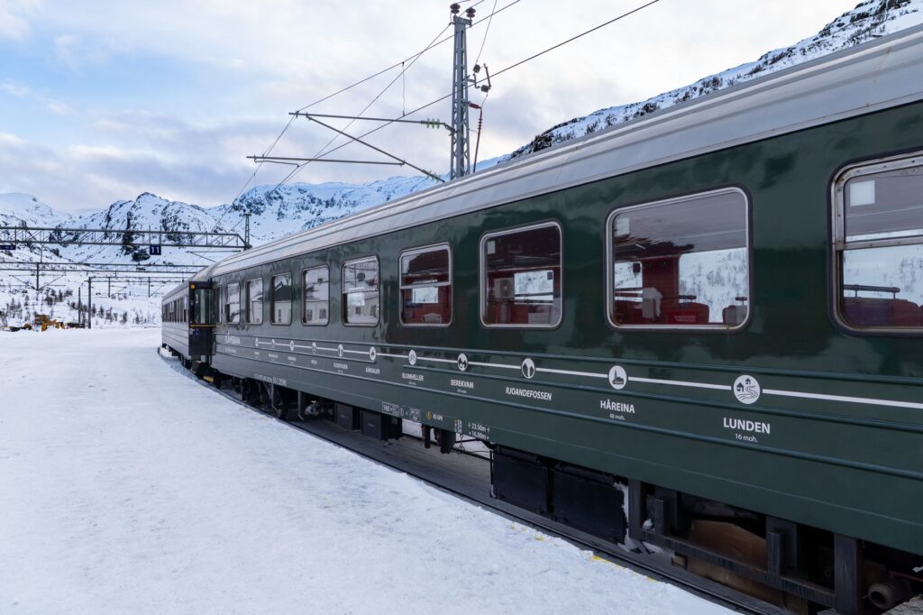 Experience a scenic train journey through the snowy landscapes of Flåm, Norway.