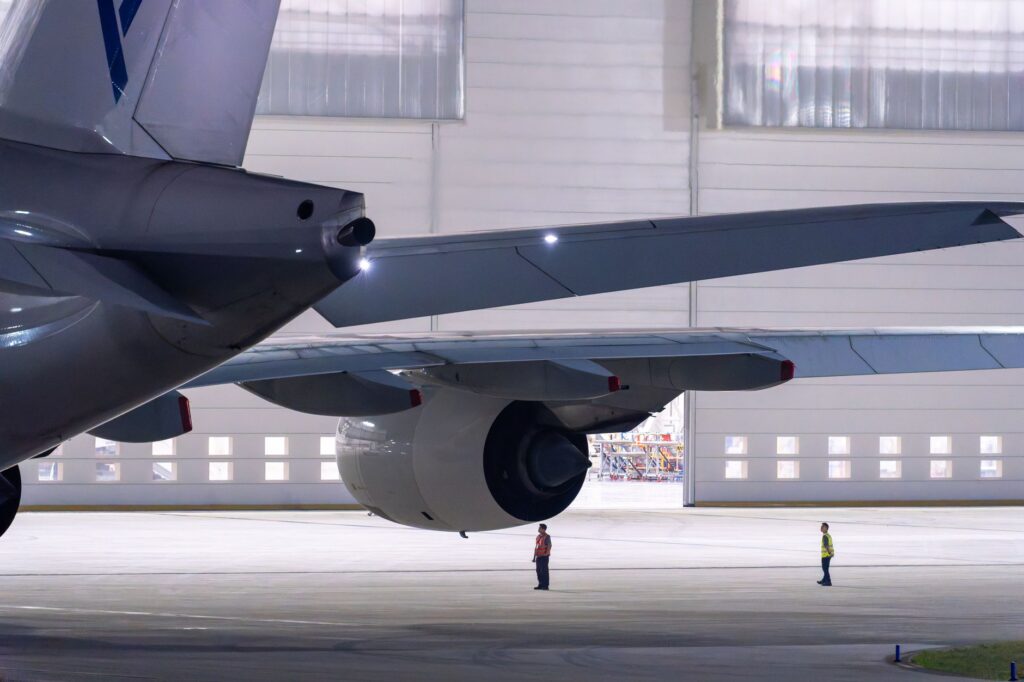 View of maintenance crew inspecting an airplane in a hangar.