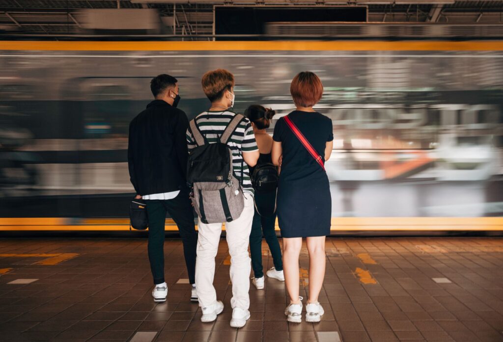 Masked commuters at Manila train station with motion blur of passing train