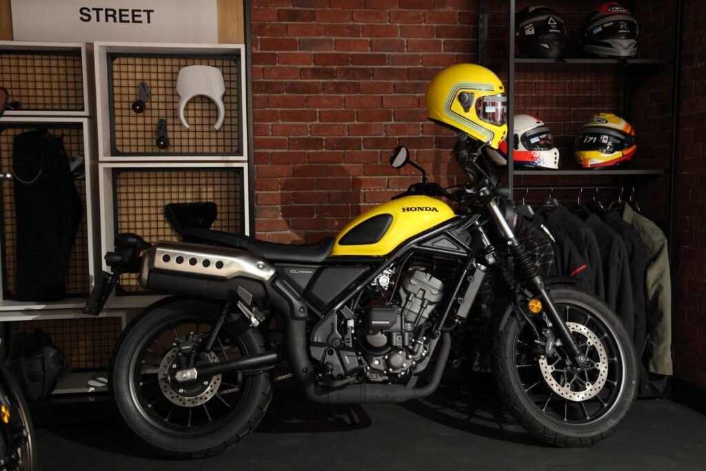 A stylish yellow Honda motorcycle parked indoors with helmets on display.