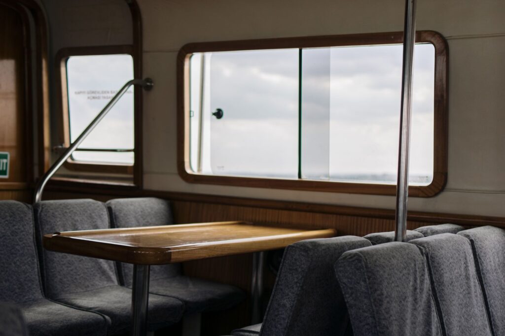 Interior view of an empty train compartment featuring a table and cushioned seats by a window.