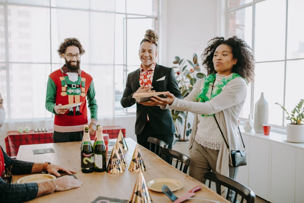 Diverse coworkers enjoy a festive office party with food, drinks, and cheerful decorations.
