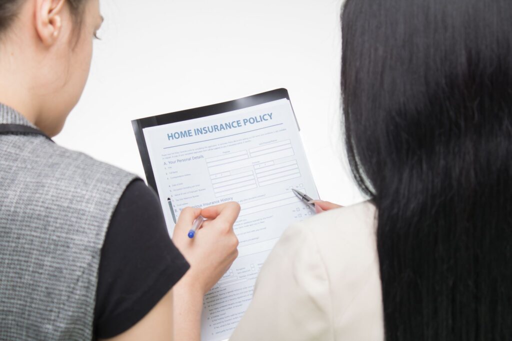 Two women examining home insurance policy form, focused on details.