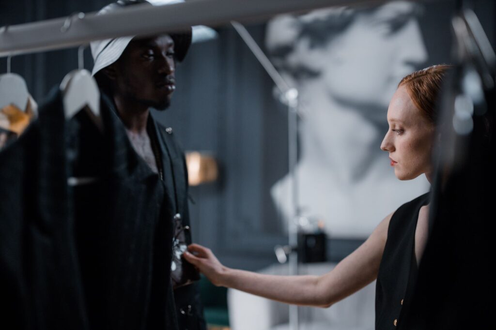 Two fashion designers working on clothing in modern studio, creating a stylish appearance.