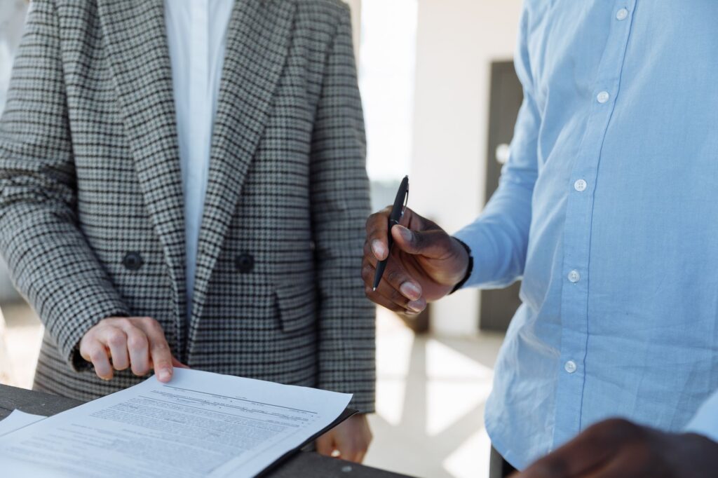 Two professionals reviewing business documents and discussing details in an office setting.