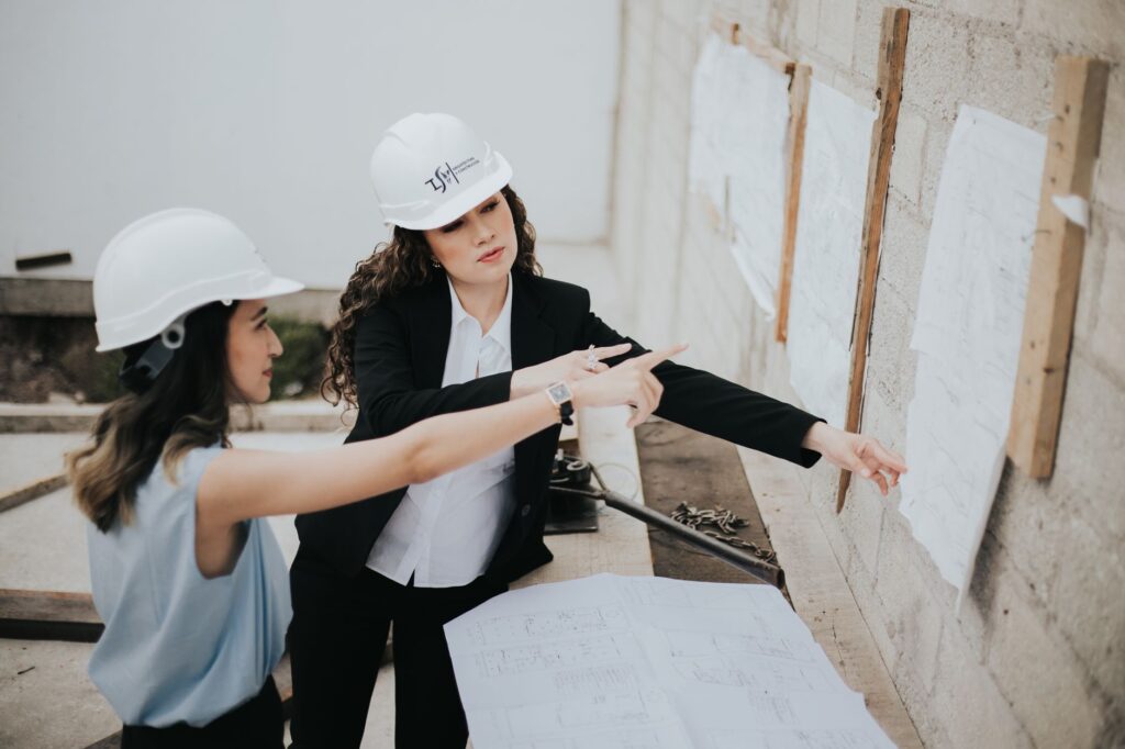 Two female architects discussing building plans outdoors, emphasizing teamwork and women leadership.